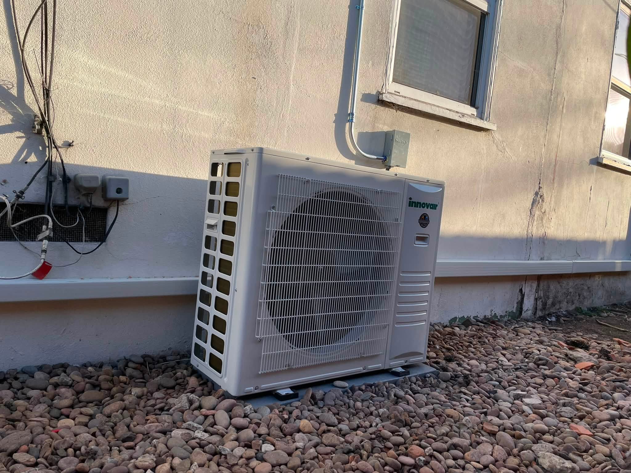 Innovair outdoor heat pump condenser installed beside a home